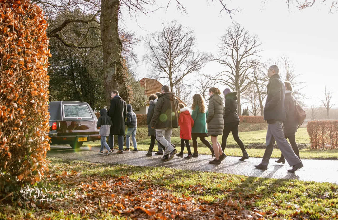 Mensen die achter een rouwauto lopen